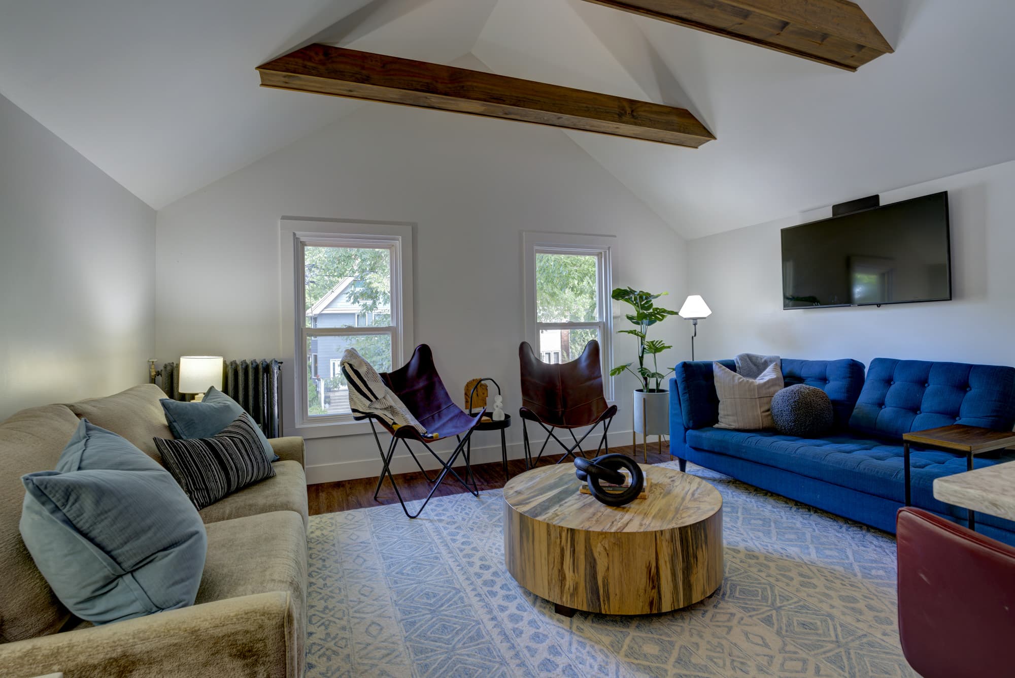 Living room with blue sofa, leather butterfly chairs, and mounted TV